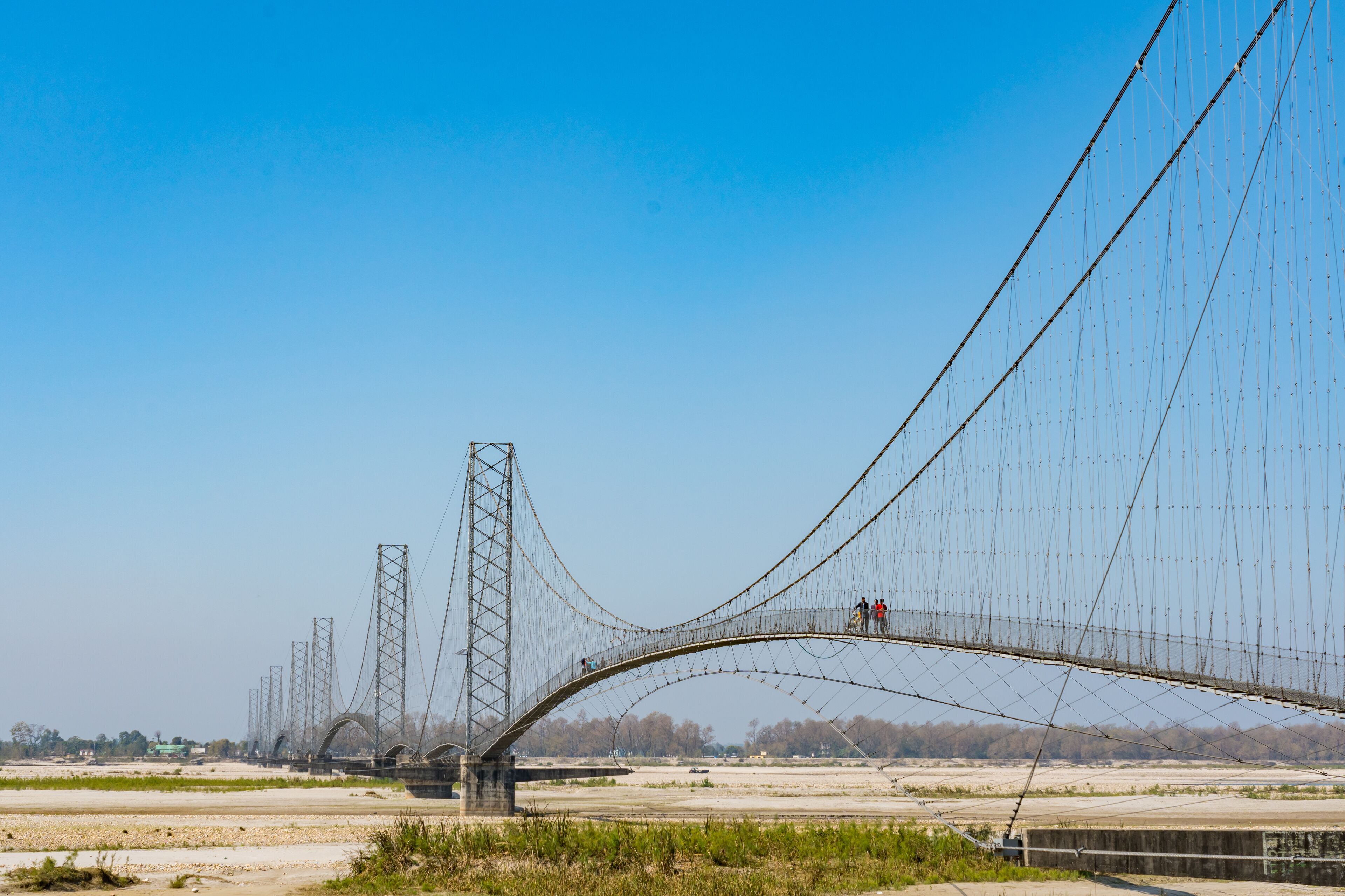 A large suspension bridge with multiple towers and cables, spanning a wide river.