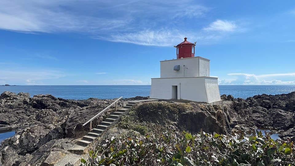 A lighthouse on rocky terrain with a clear blue sky.