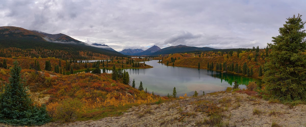 A lake surrounded by autumn-colored trees and mountains.