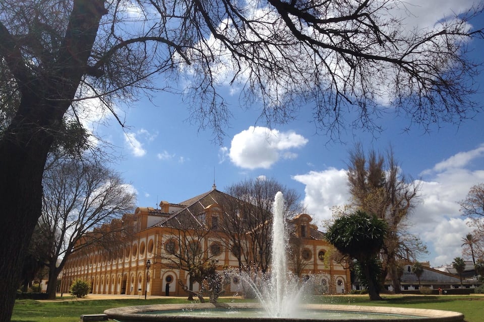 A historic building with a fountain in a landscaped garden.