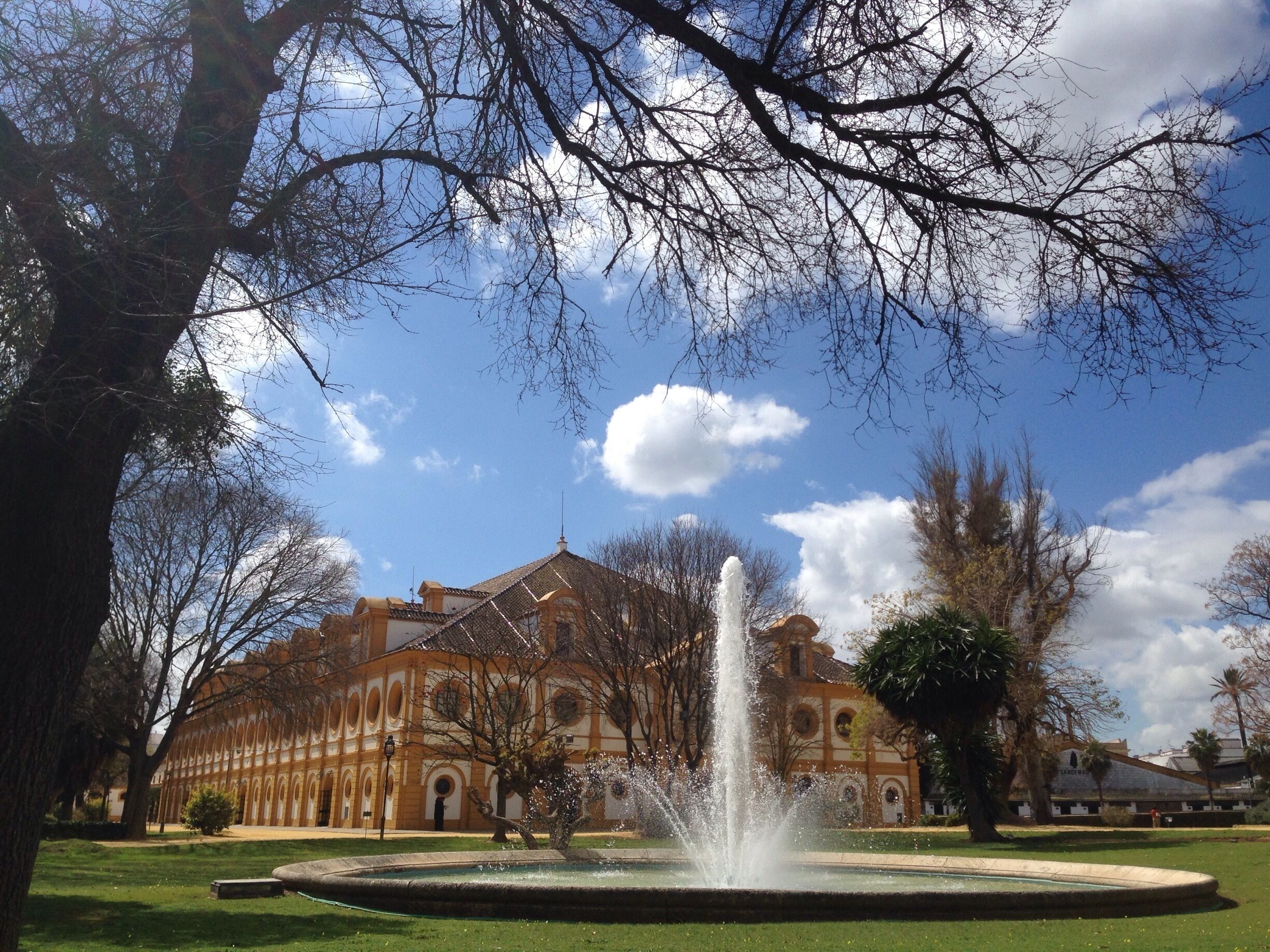 A historic building with a fountain in a landscaped garden.