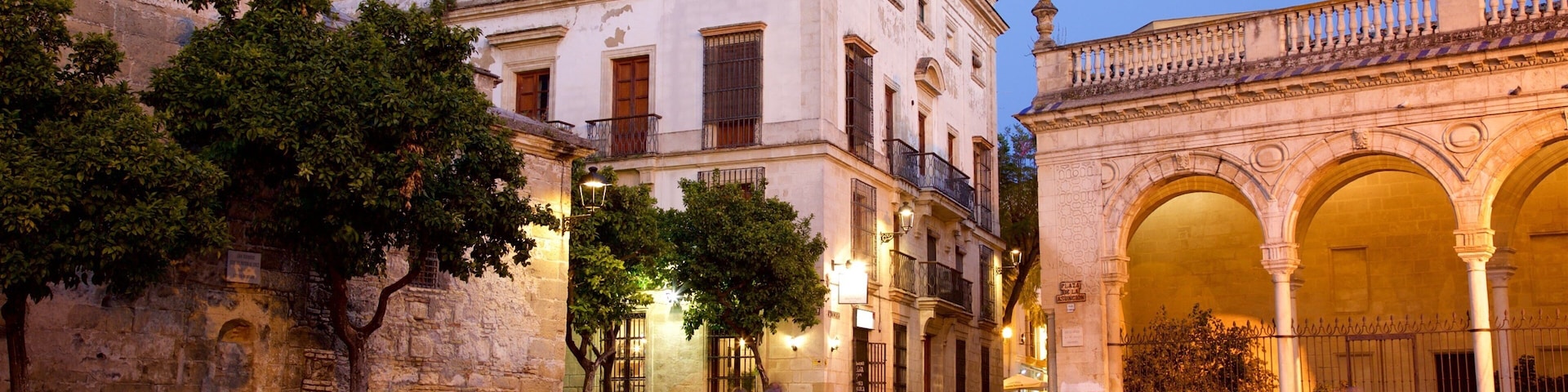 A historic square with stone buildings, outdoor seating, and an ornate archway.