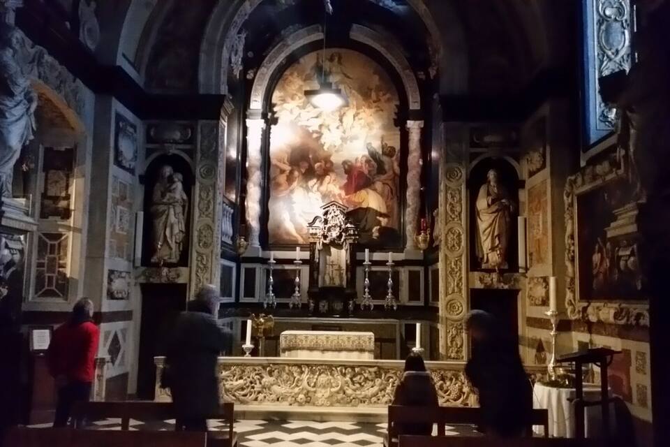 Interior ornamentado de una iglesia con un mural grande, estatuas y una araña.