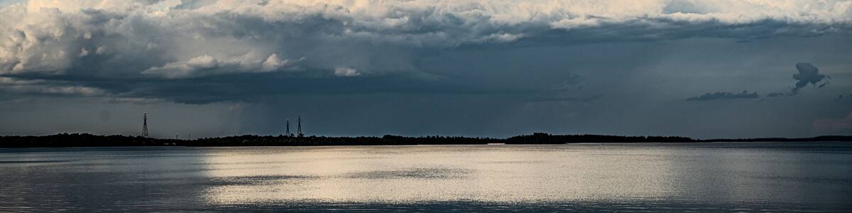 A large cloud formation over a body of water with a clear sky.