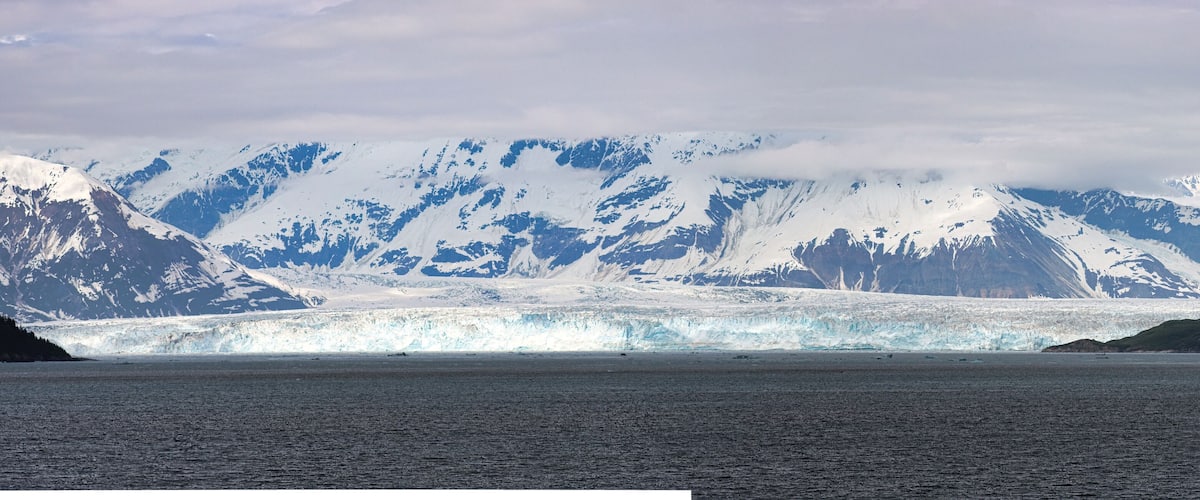 A glacier with snow-capped mountains in the background.
