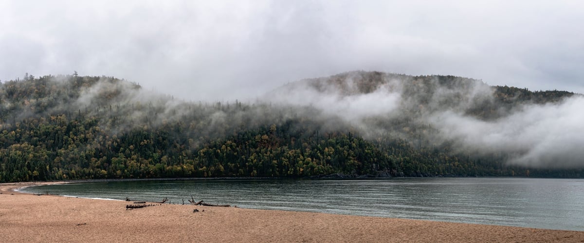 A lake with a forested mountain in the background.
