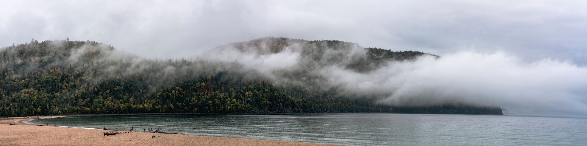 A lake with a forested mountain in the background.