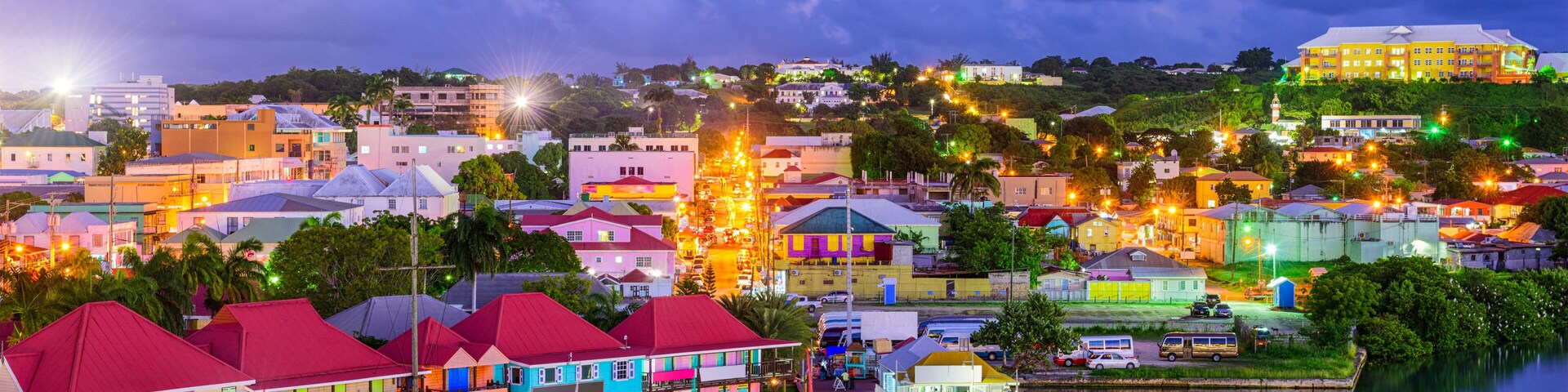 Un pueblo costero al atardecer con edificios coloridos, un puerto tranquilo y un puente que lleva al pueblo.