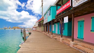 A wooden pier extending into turquoise waters, lined with colorful buildings, including a red sign welcoming to Historic Redcliffe Quay.