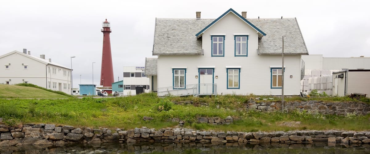 A coastal house with a lighthouse in the background.