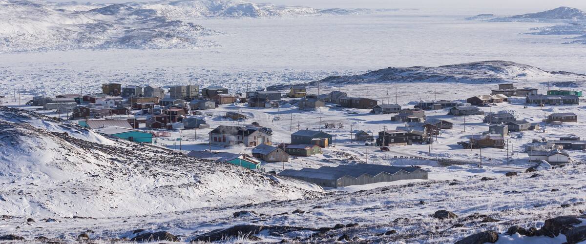 A snow-covered town with buildings and a mountainous backdrop.