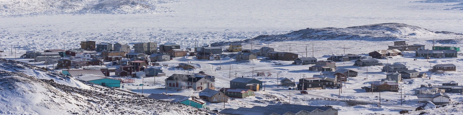 A snow-covered town with buildings and a mountainous backdrop.