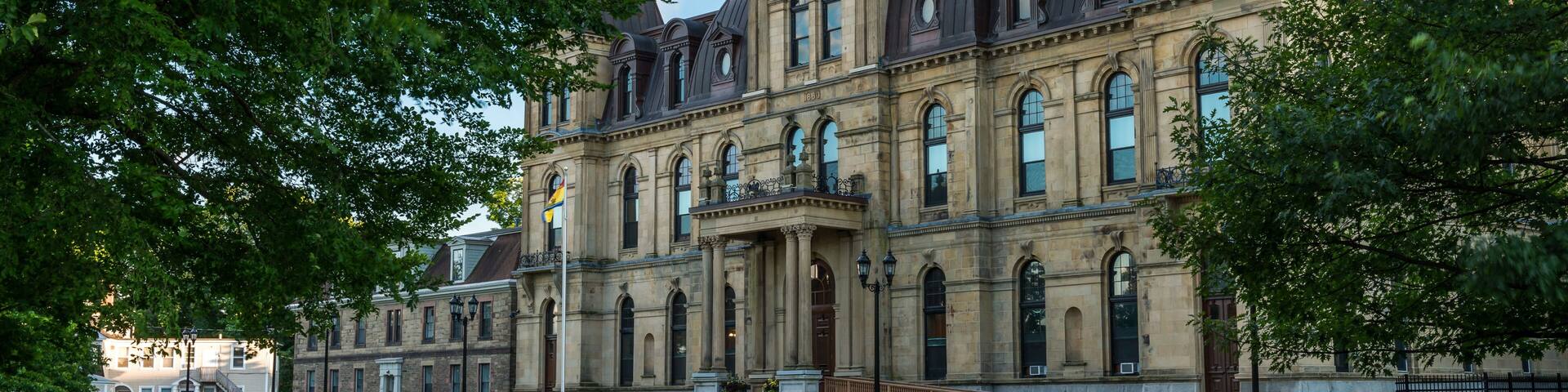 A historic building with a prominent dome and two towers, surrounded by well-maintained lawns and trees.