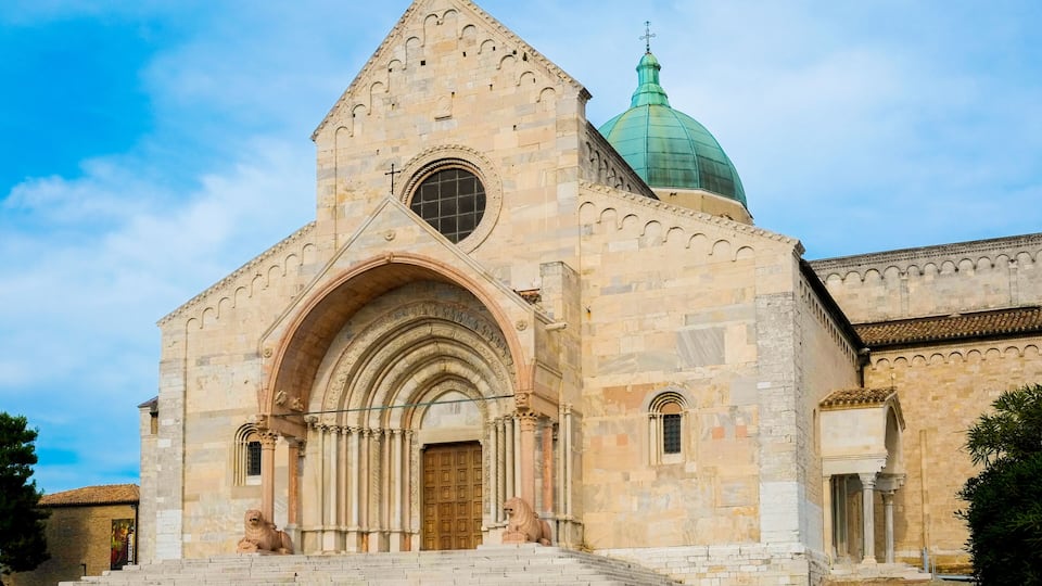 A historic church with a prominent green dome and a lion statue at the entrance.