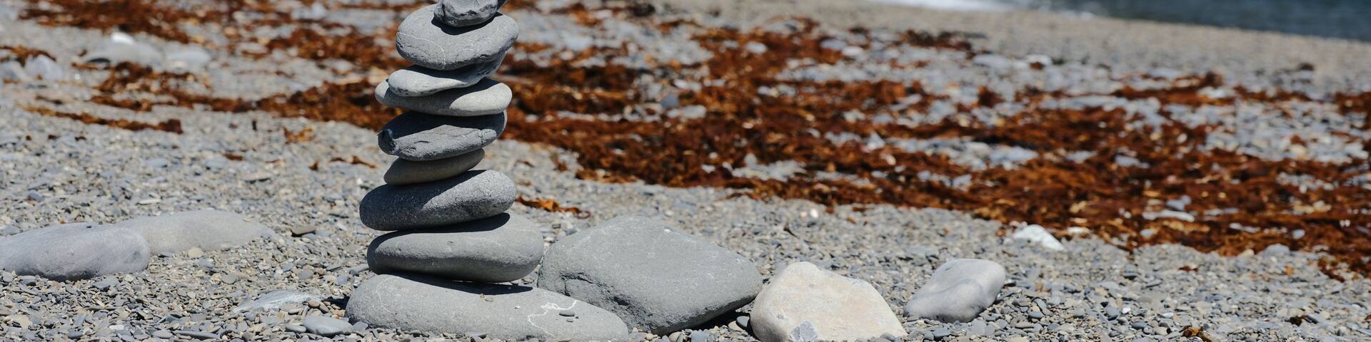 Panorama image of a Rock Cairn on the beach at the Cap-des-Rosiers Lighthouse at La Cote-de-Gaspe, Gaspe Peninsula on the Gulf of St. Lawrence Quebec Canada