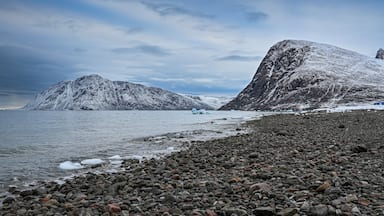 Una costa rocosa con un glaciar al fondo.