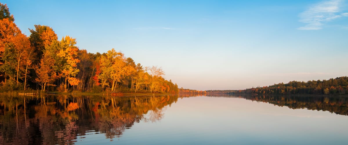 A calm lake reflecting autumn trees.
