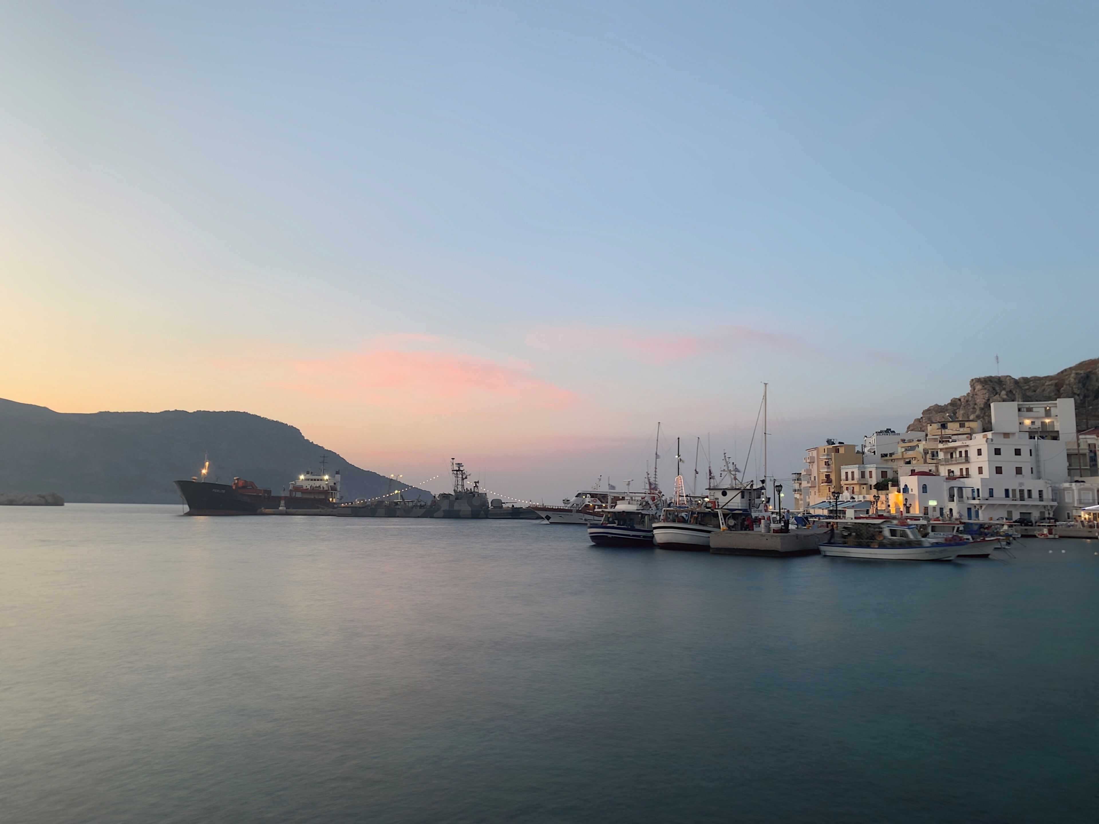 A harbor with boats and buildings at sunset.