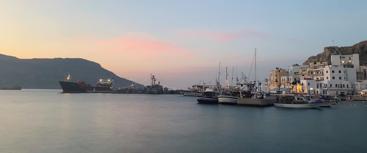 A harbor with boats and buildings at sunset.