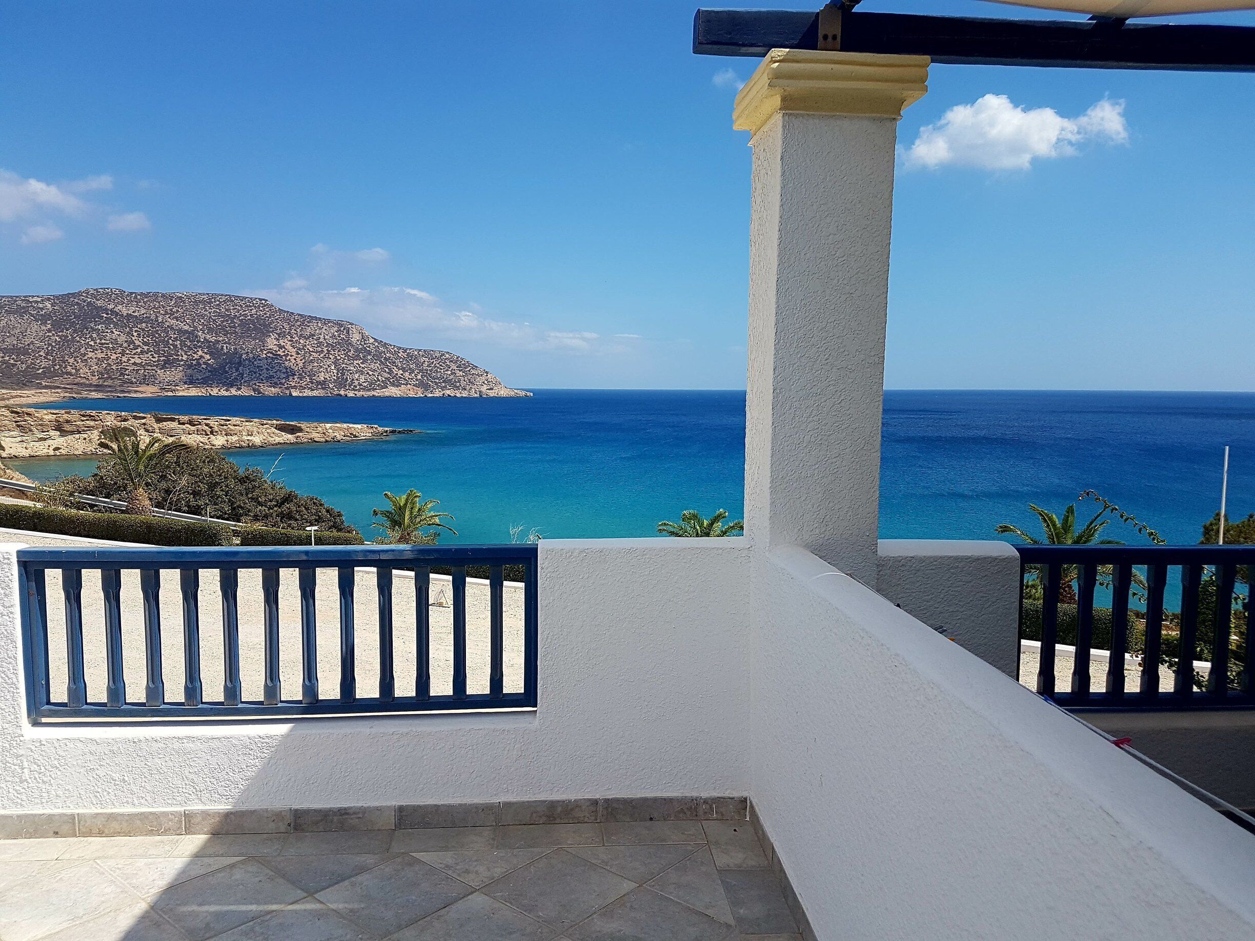 A coastal view with a clear sky, a rocky hill, and the sea.