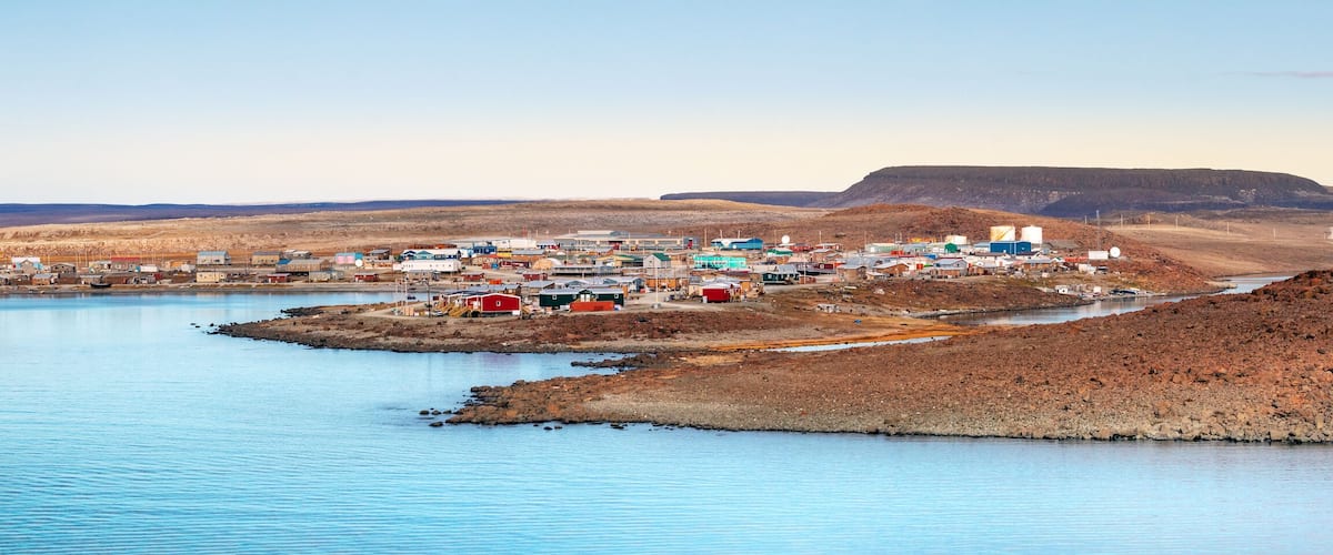 A coastal town with buildings and a rocky island in the water.