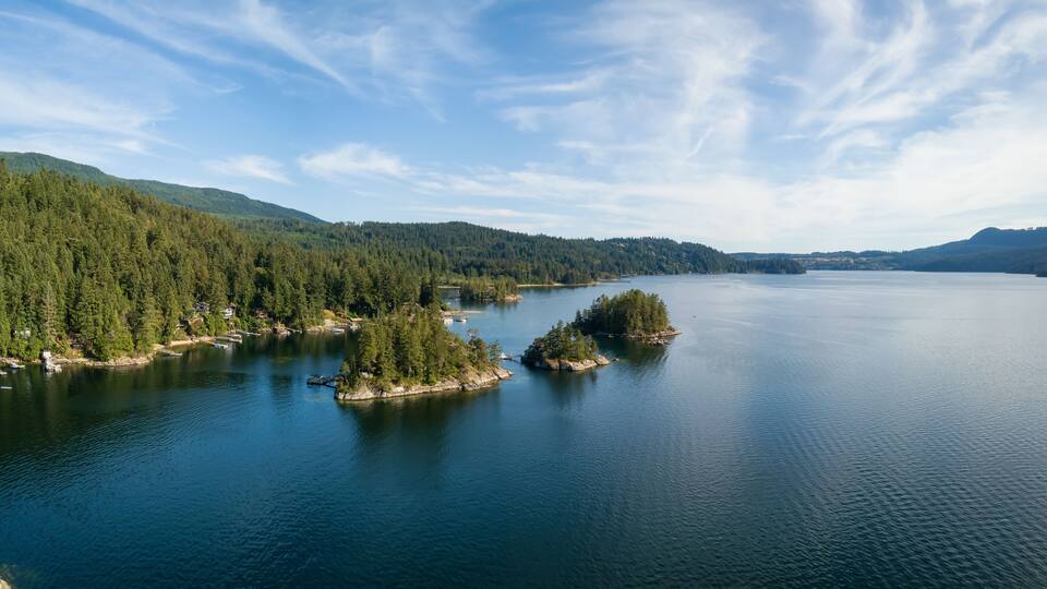 A calm lake surrounded by dense forests and small islands.
