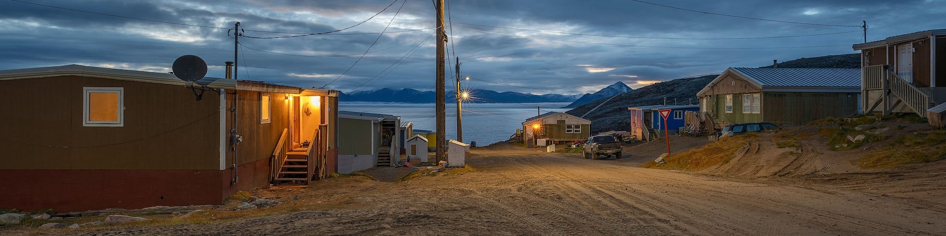 Early morning illuminated street of houses in Pond Inlet Mittimatalik) with the Byam Martin Mountains in the background