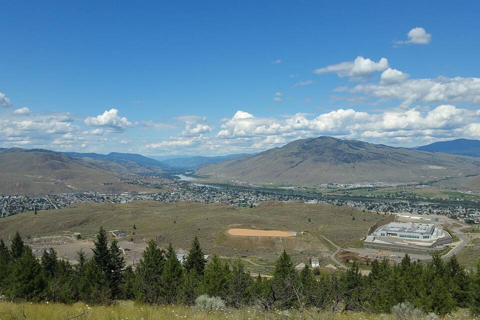 A mountainous landscape with a town, a river, and a large building.