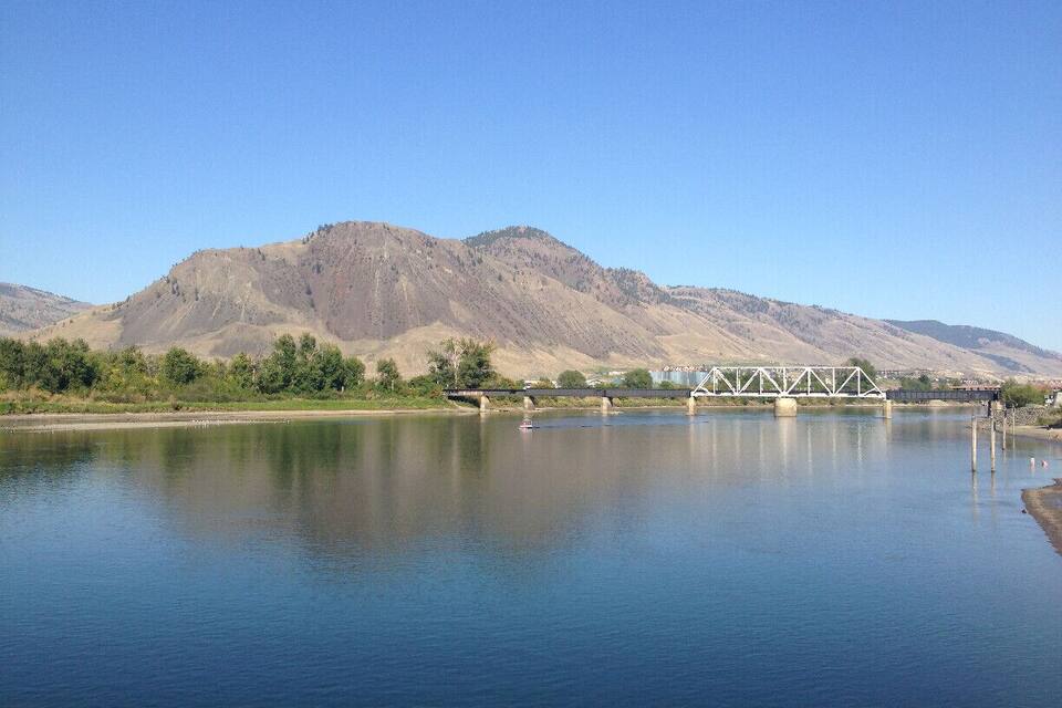 A calm lake with a bridge and mountains in the background.