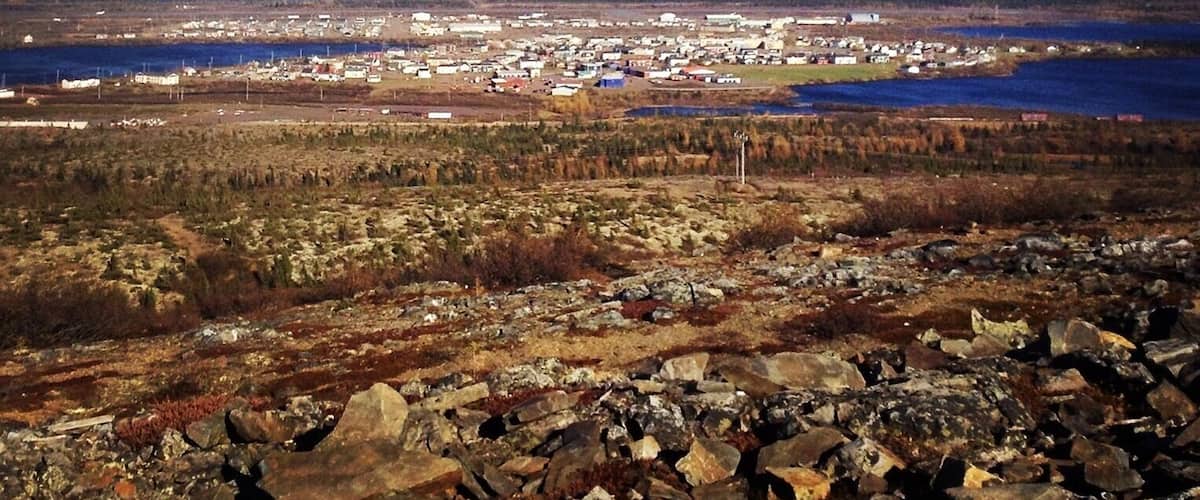 A coastal town with a clear sky, surrounded by rocky terrain and a body of water.