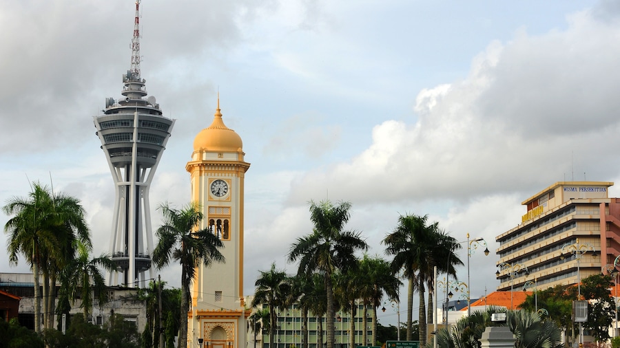 Una torre con un reloj, una torre moderna y palmeras.