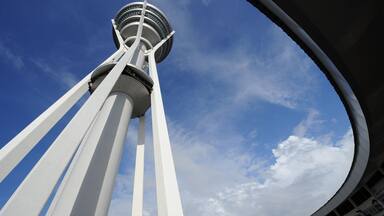 Una torre con elementos estructurales blancos y una plataforma de observación circular contra un cielo azul con nubes.
