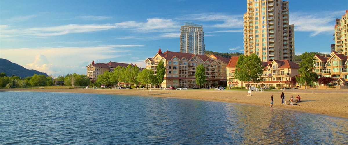 Kelowna featuring a lake or waterhole and a sandy beach as well as a small group of people