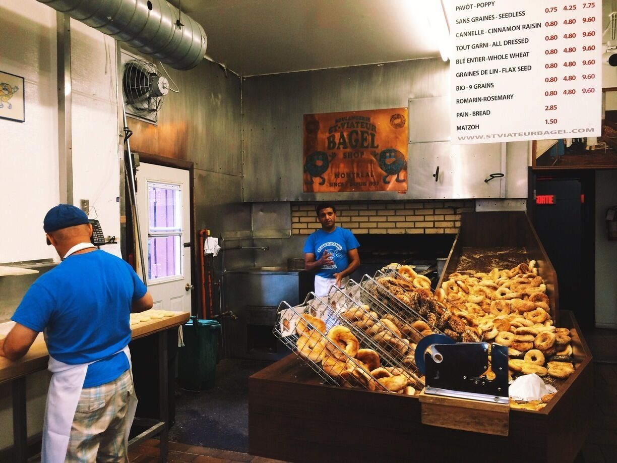 A bakery with a variety of bagels displayed in a rack and a menu listing prices.