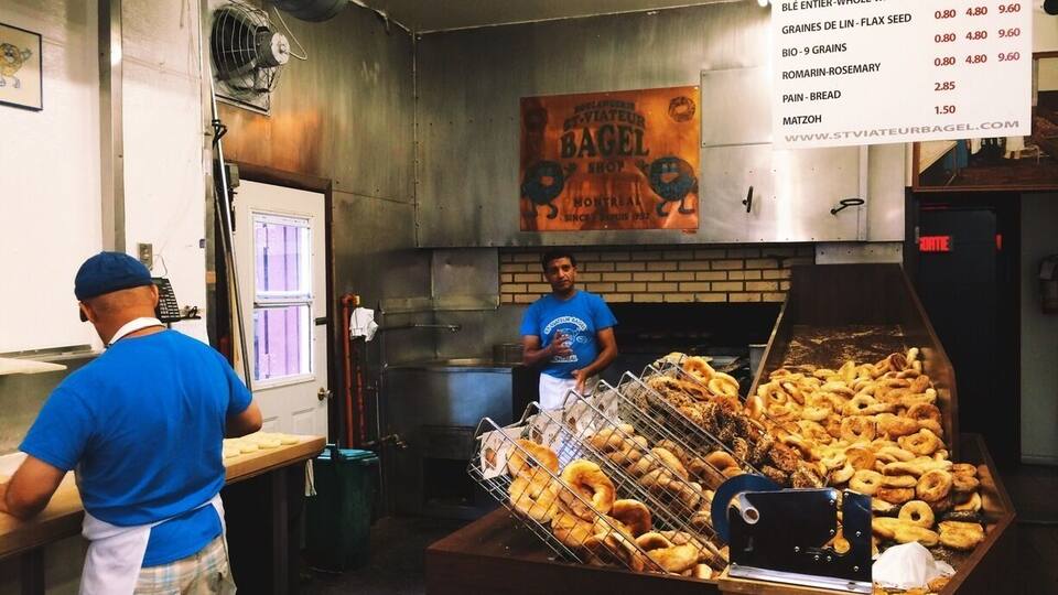 A bakery with a variety of bagels displayed in a rack and a menu listing prices.