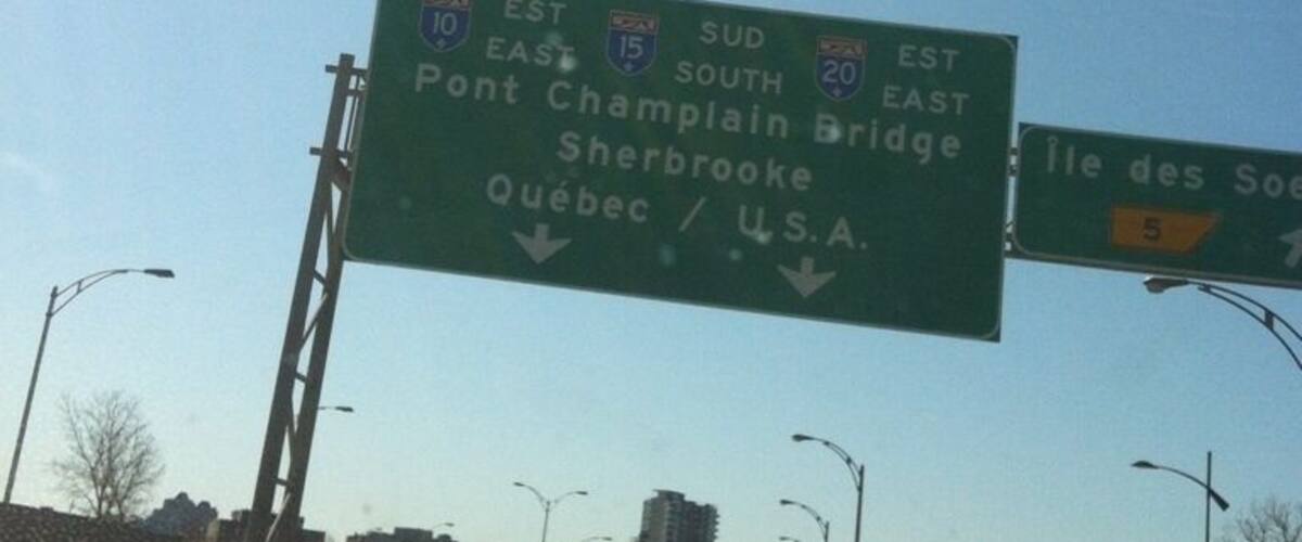 A highway sign with directions to Pont Champlain Bridge, Sherbrooke, Quebec, and the U.S.A.
