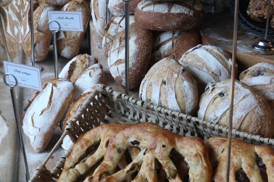 A variety of breads displayed in a bakery case.