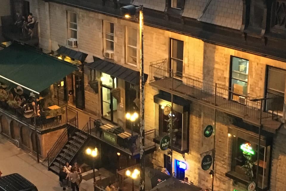 A street scene with a building featuring a green awning, outdoor seating, and a visible storefront.