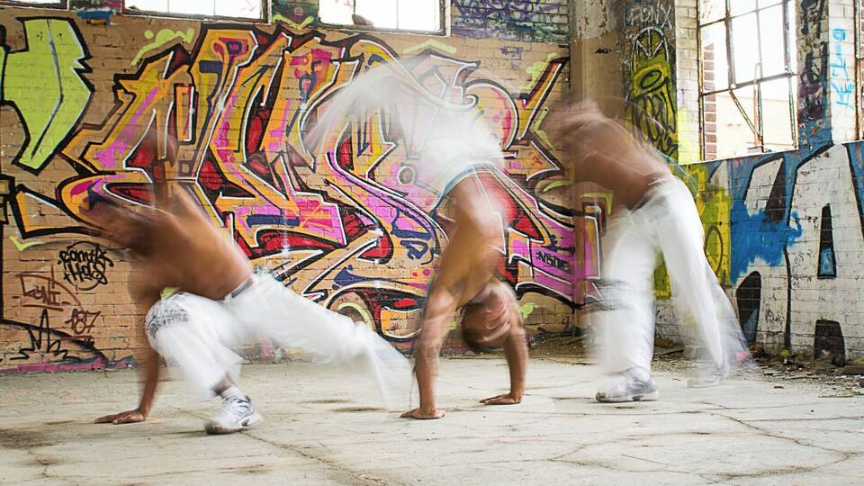 A graffiti-covered wall with a person performing a handstand.