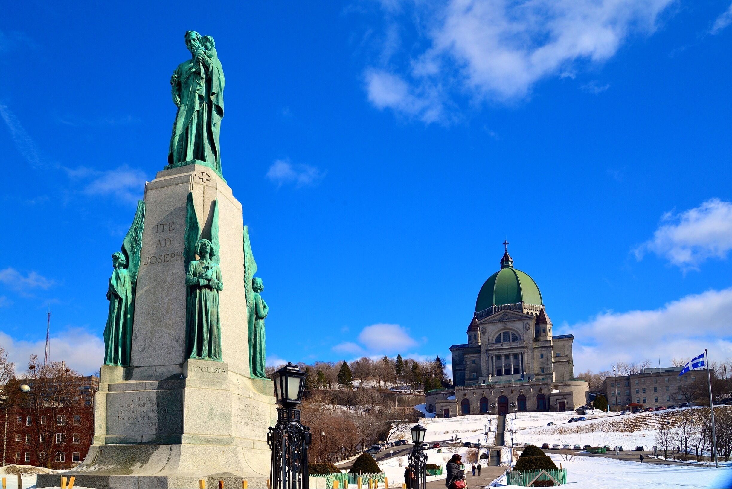 A statue of a man and a building with a green dome.