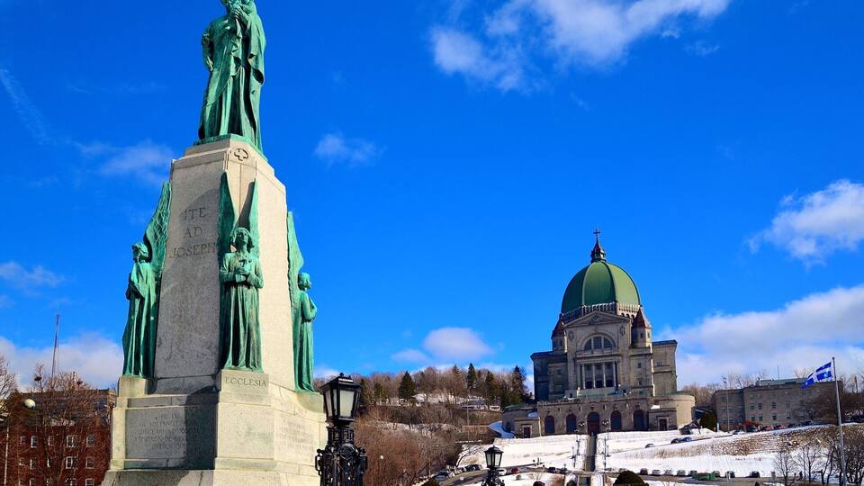Une statue d’un homme et un bâtiment surmonté d’un dôme vert.