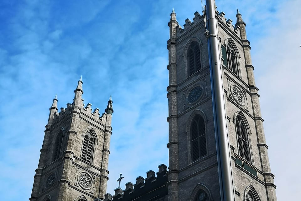A historic church with twin towers and a flagpole with a Canadian flag.