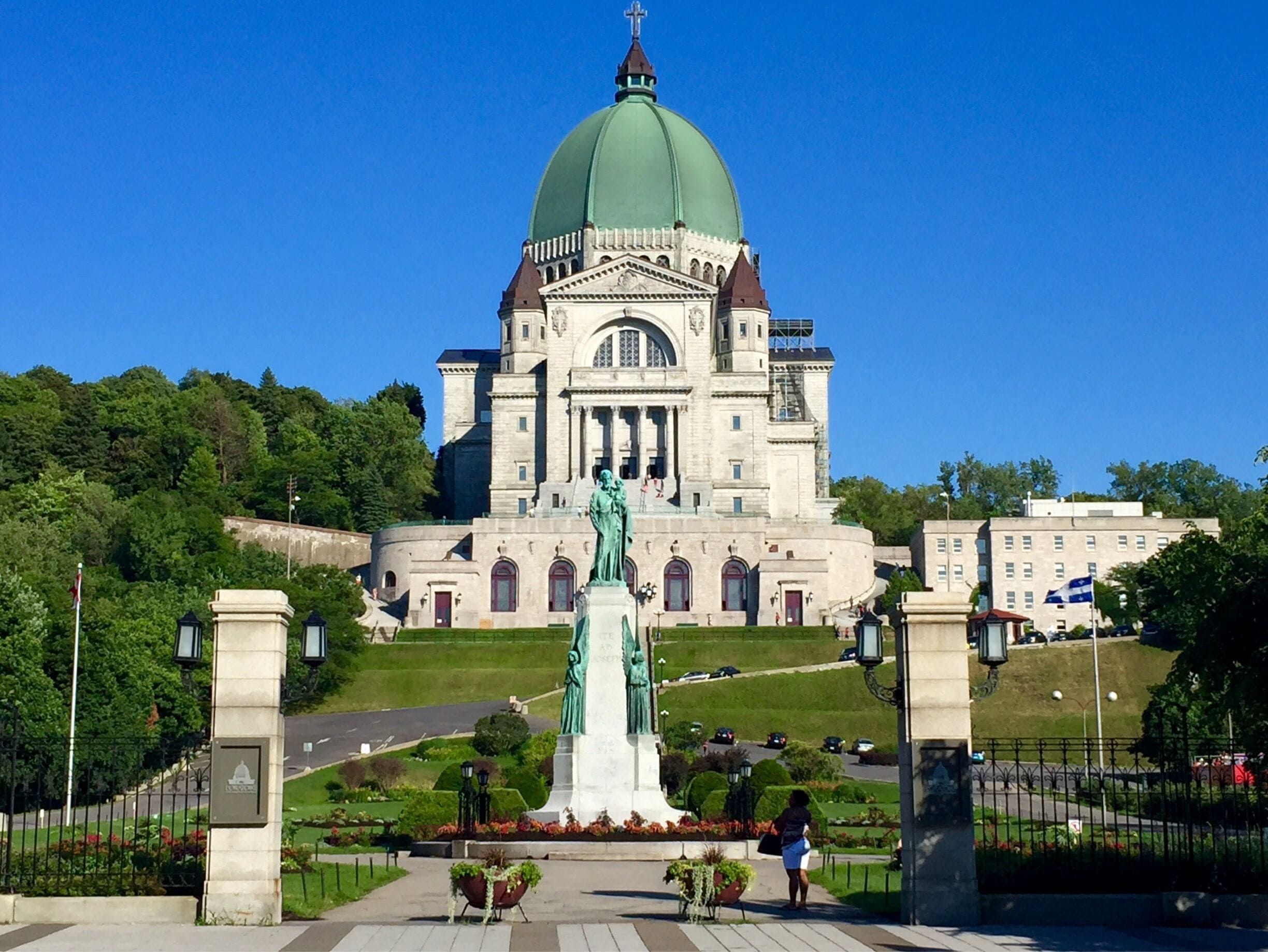 A large building with a green dome and a statue in front.