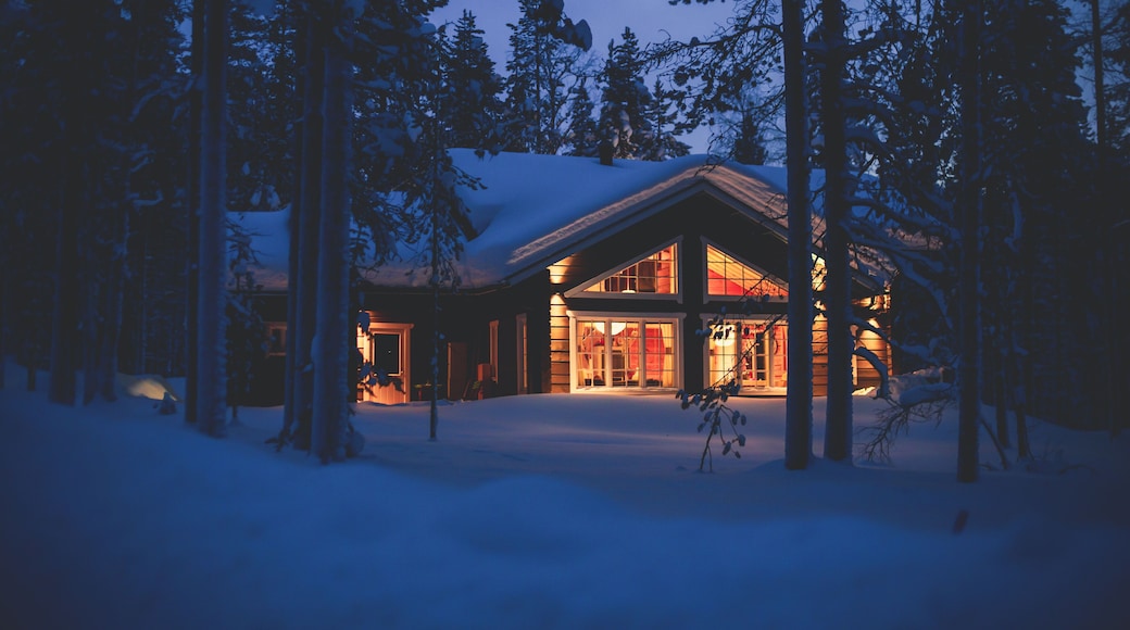A cozy wooden cabin cottage chalet house covered in snow near ski resort in winter with the lights turn on
