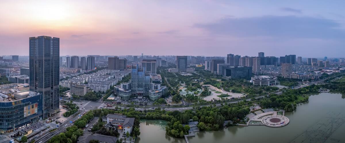 A cityscape with high-rise buildings, a river, and a park with a circular monument.