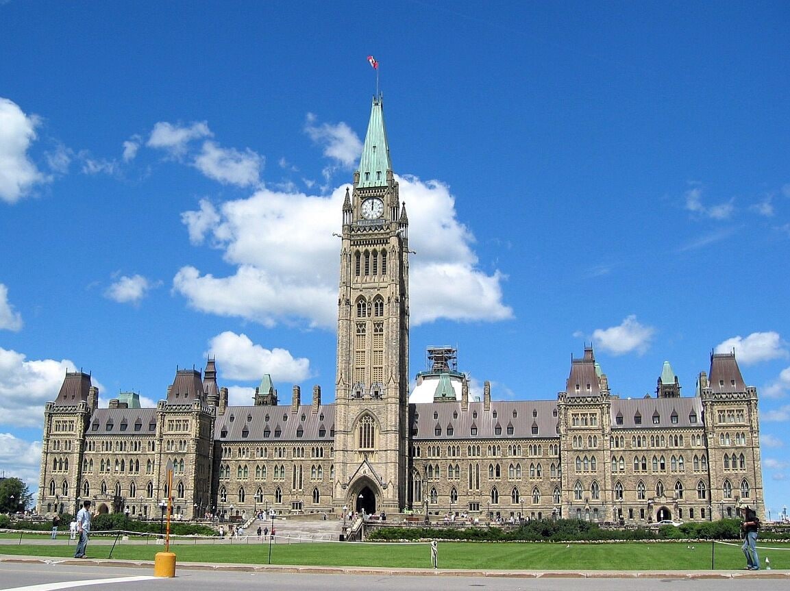 A large historic building with a prominent clock tower and a flag on top.