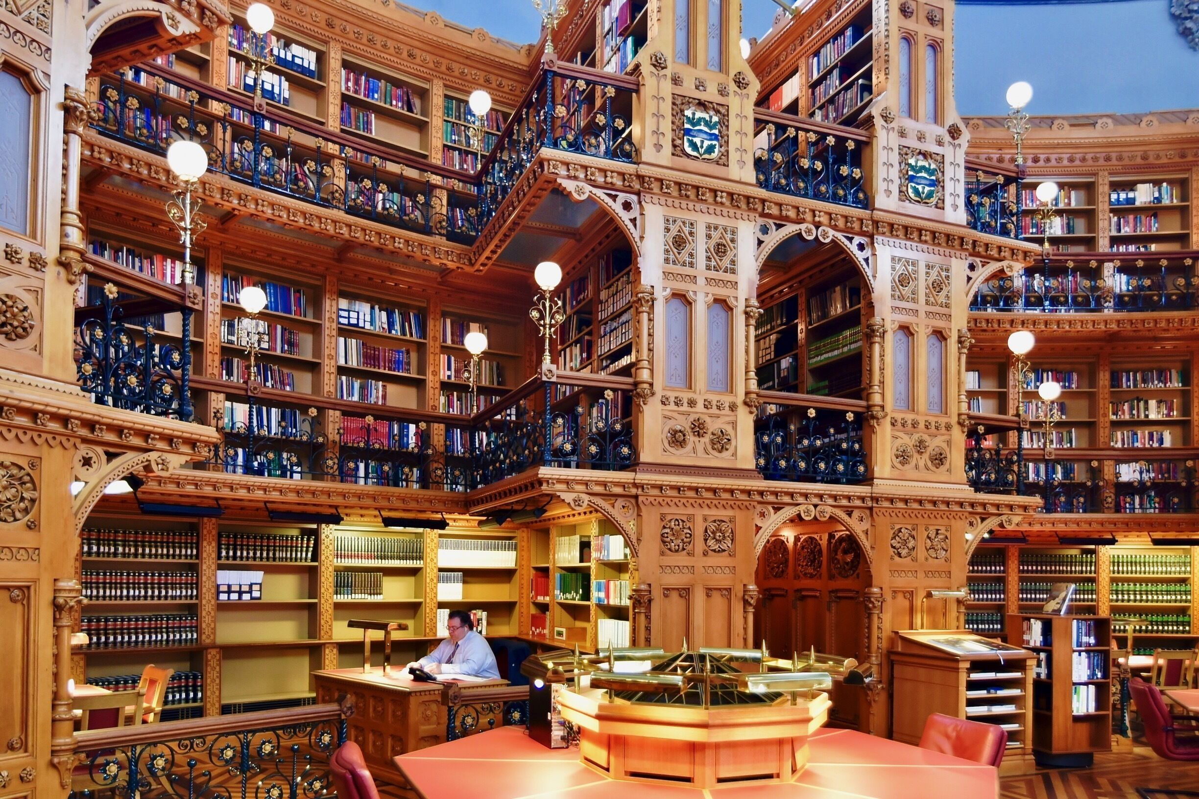 An ornate library with multiple levels of bookshelves and a central reading area.