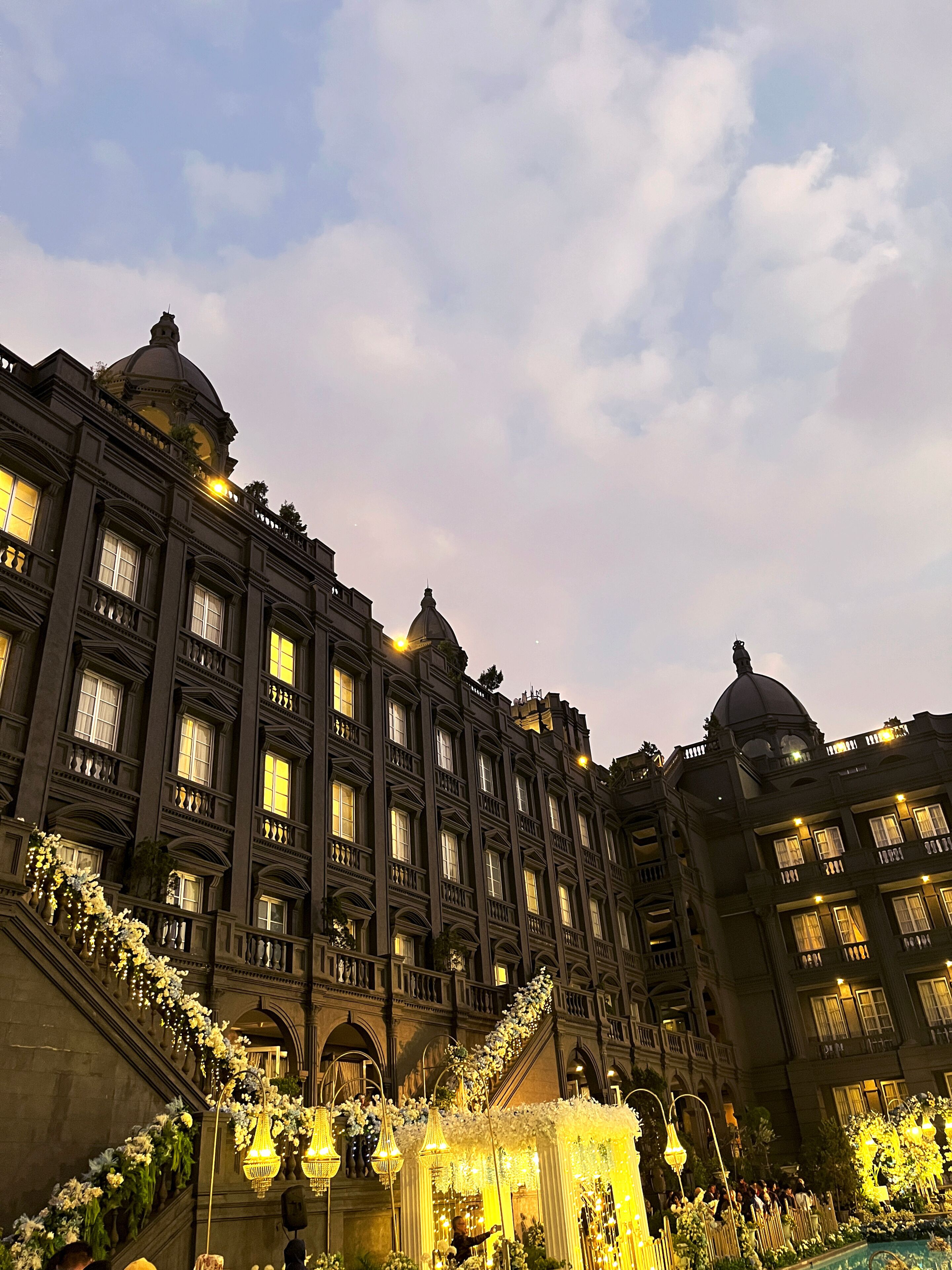 Un edificio imponente con numerosas ventanas y balcones, detalles ornamentales y una gran cúpula.