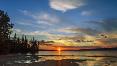 lake and red sunset glow, sun rays, black silhouettes of trees and reflection