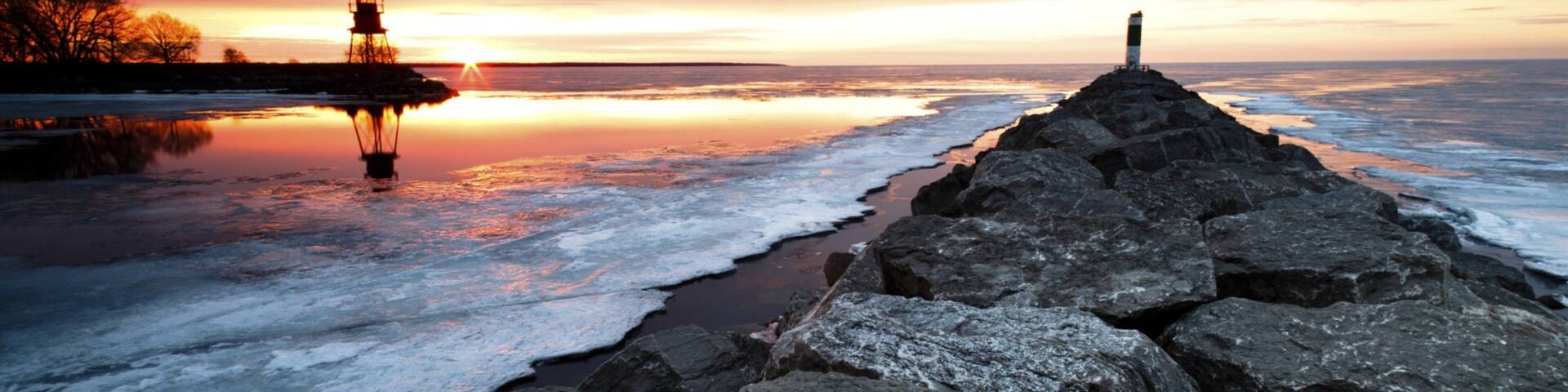 Alpena que inclui um pôr do sol, neve e um farol